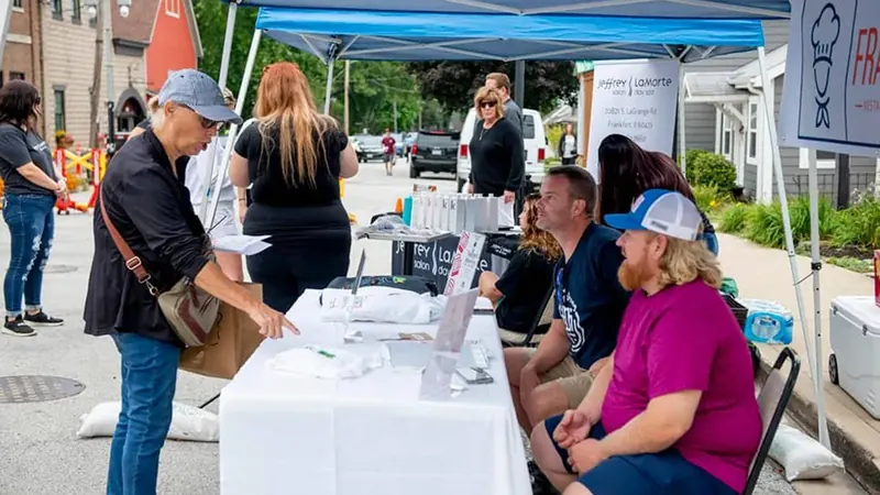 Visitors stopping at the Frankfort Restaurant Week booth at an outdoor event