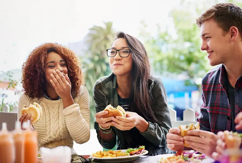 Three friends laughing over burgers at a restaurant