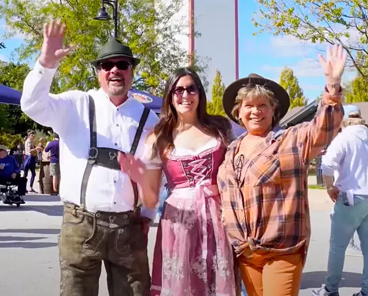 Three guests in Oktoberfest dress waving at the Second Annual Frankforter Oktoberfest